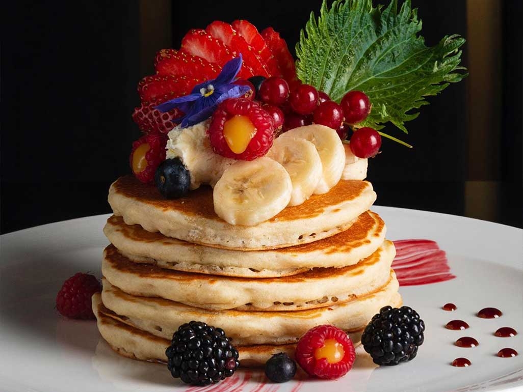 A stack of fluffy american pancakes with fresh fruit