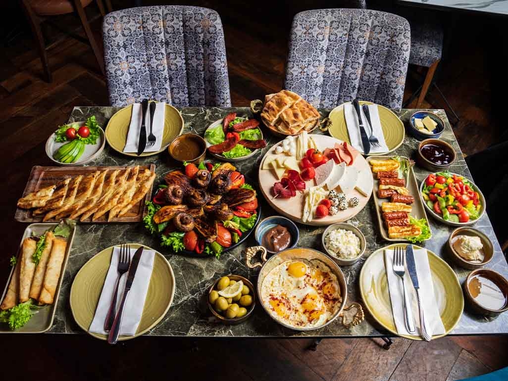 Lots of plates of food including salads, olives and a cheeseboard