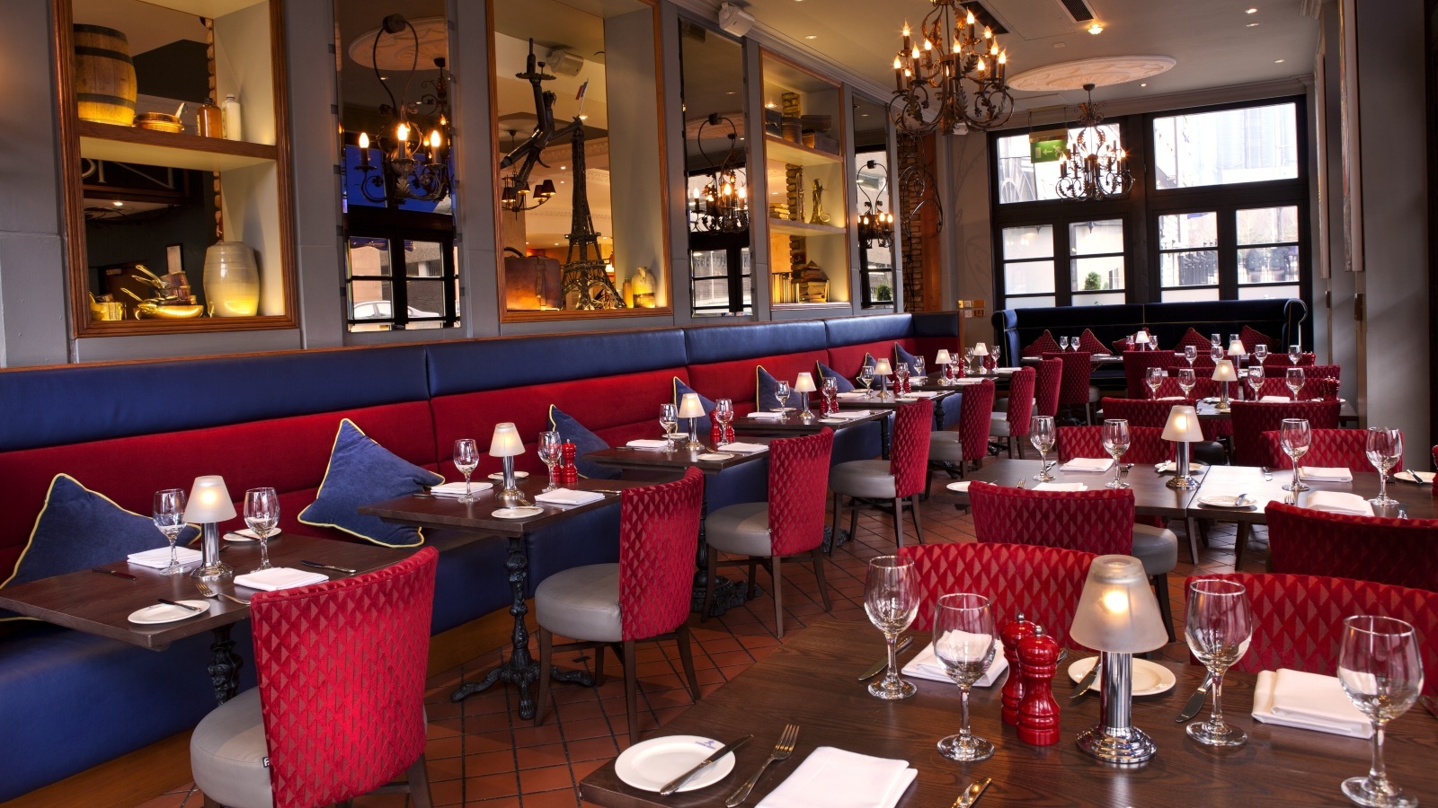 Empty restaurant set up ready for dinners with lamps and wine glasses on table. 