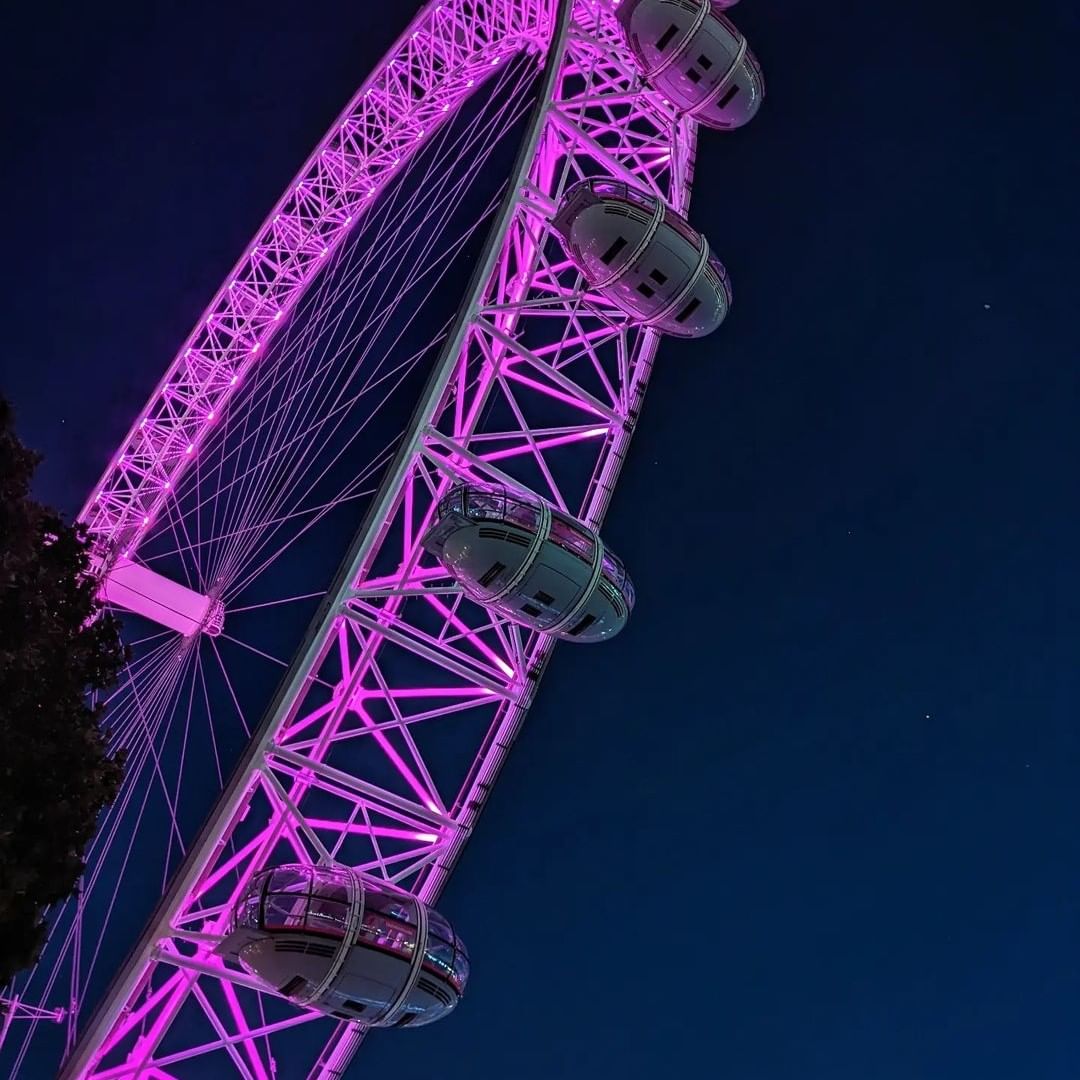 The London Eye at night time, lit up with purple neon lights
