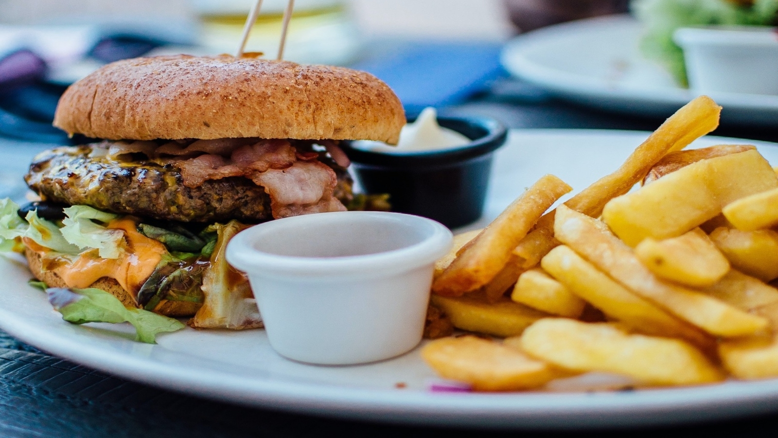 A beef, bacon burger with fries on the side