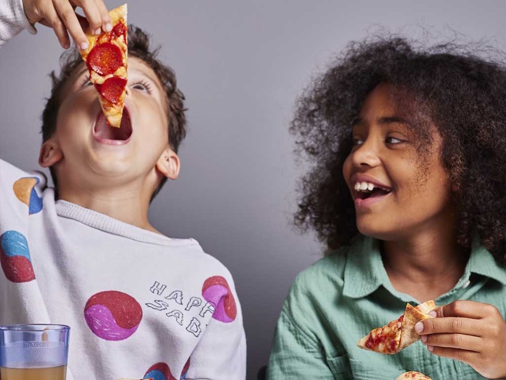 Children eating a slice of pepperoni pizza