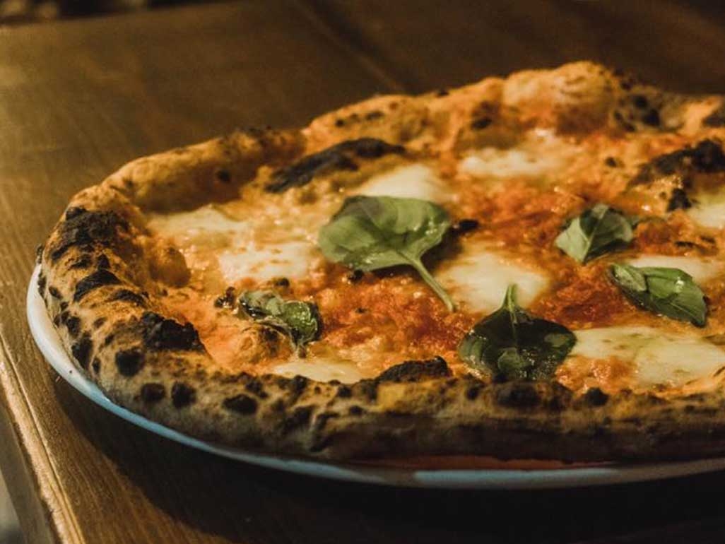 An authentic margarita pizza served with fresh basil