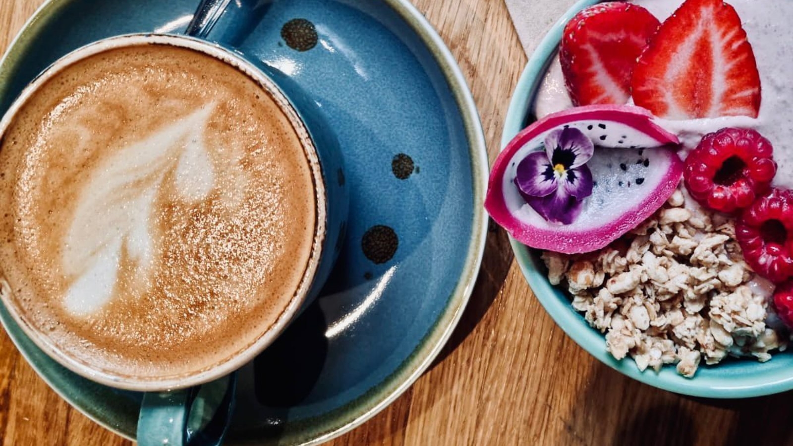 Latte with a granola bowl and fruit