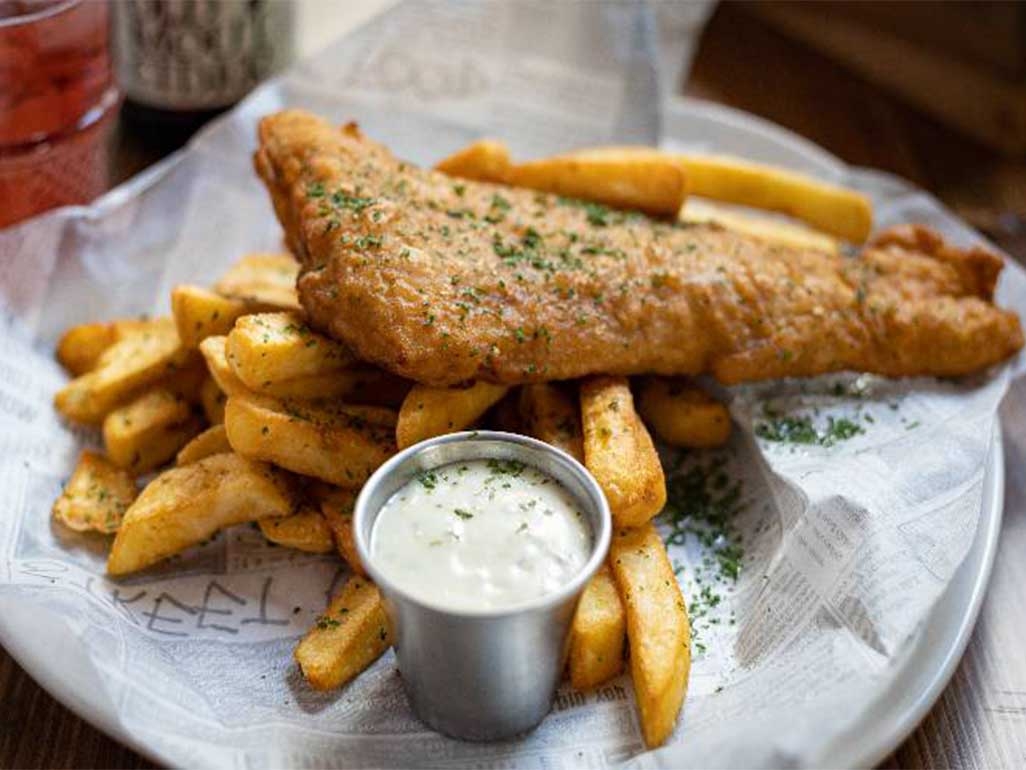 Fish and chips with seasonings and a side portion of tartare sauce