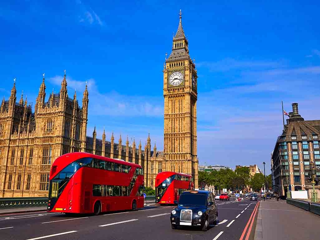 London's Big Ben on a sunny day featuring iconic London red buses and black taxi cab 